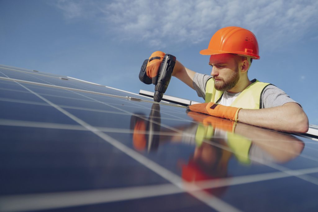 Technician installing solar photovoltaic (PV) electric panels 