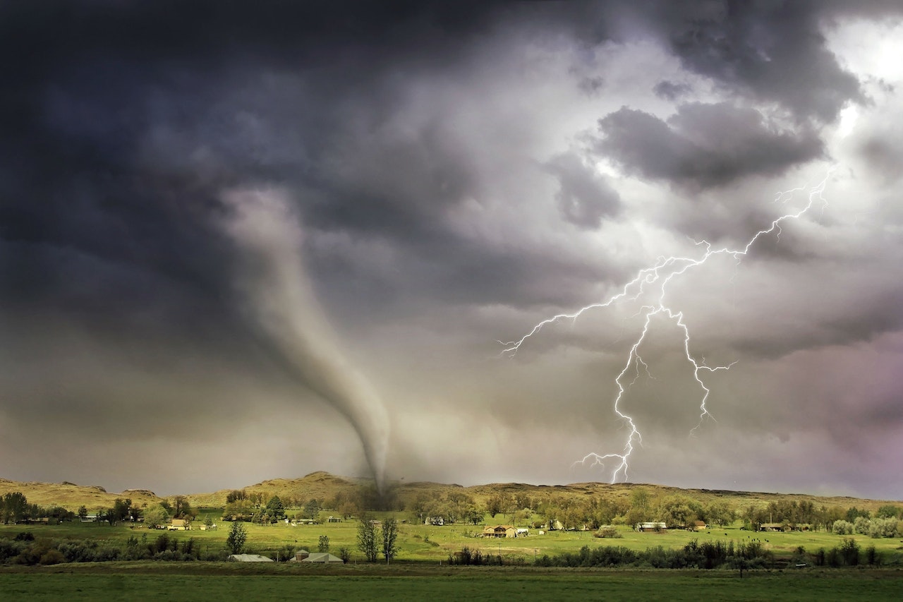 Tornado touching down in a field with lighting cracks in sky