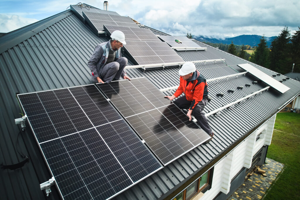 Two men install solar powered tiles on a roof