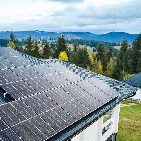 Solar panel array installed on a rooftop with mountain views in the background